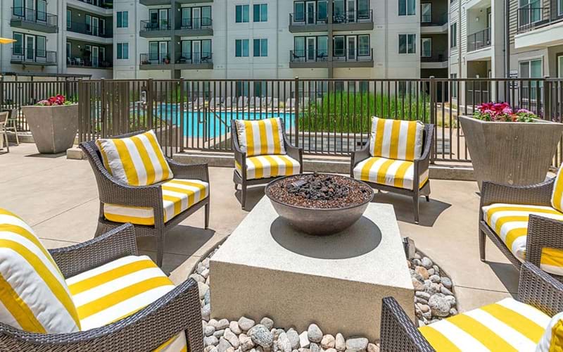 wicker chairs surround outdoor fire pit near pool